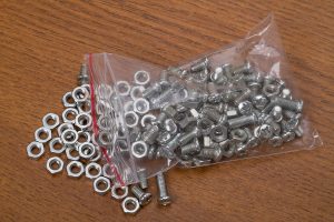 Plastic bag with small nuts and bolts on the brown table